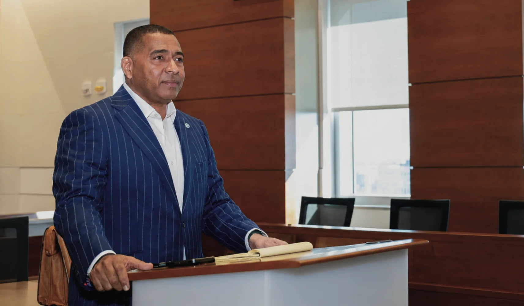 An attorney in a pinstripe suit standing at a courtroom lectern